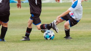 Barn i svarta och vita dräkter spelar fotboll.